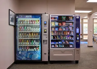 Deux distributeurs automatiques de boissons et de snacks alignes dans un couloir