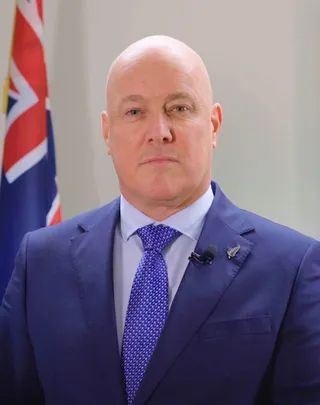 Portrait officiel de Christopher Luxon, Premier ministre de Nouvelle-Zélande, devant le drapeau national
